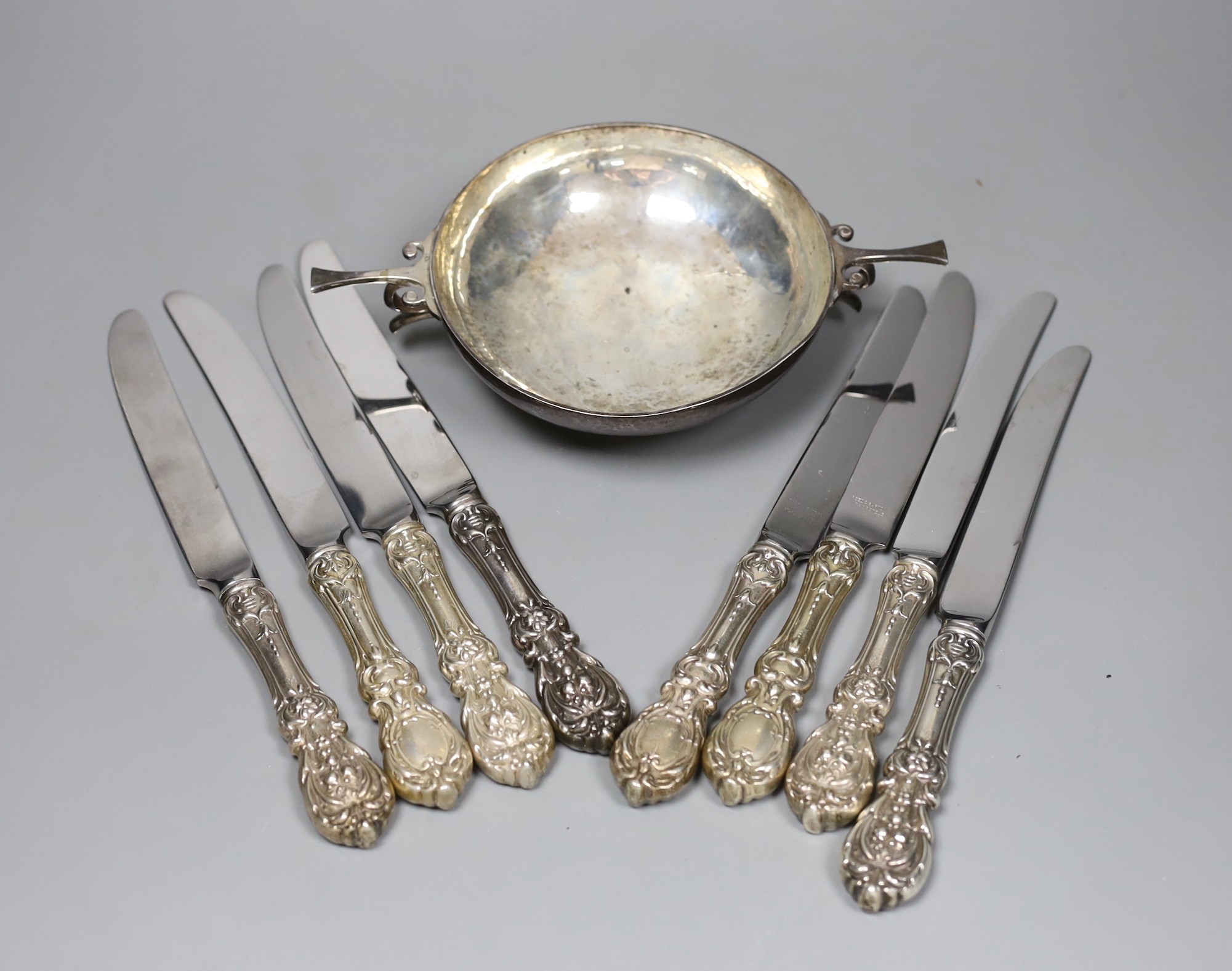A George V silver porringer, with planished decoration, London 1910, 22cm, 247 grams and eight Reed and Barton table knives with plated handles